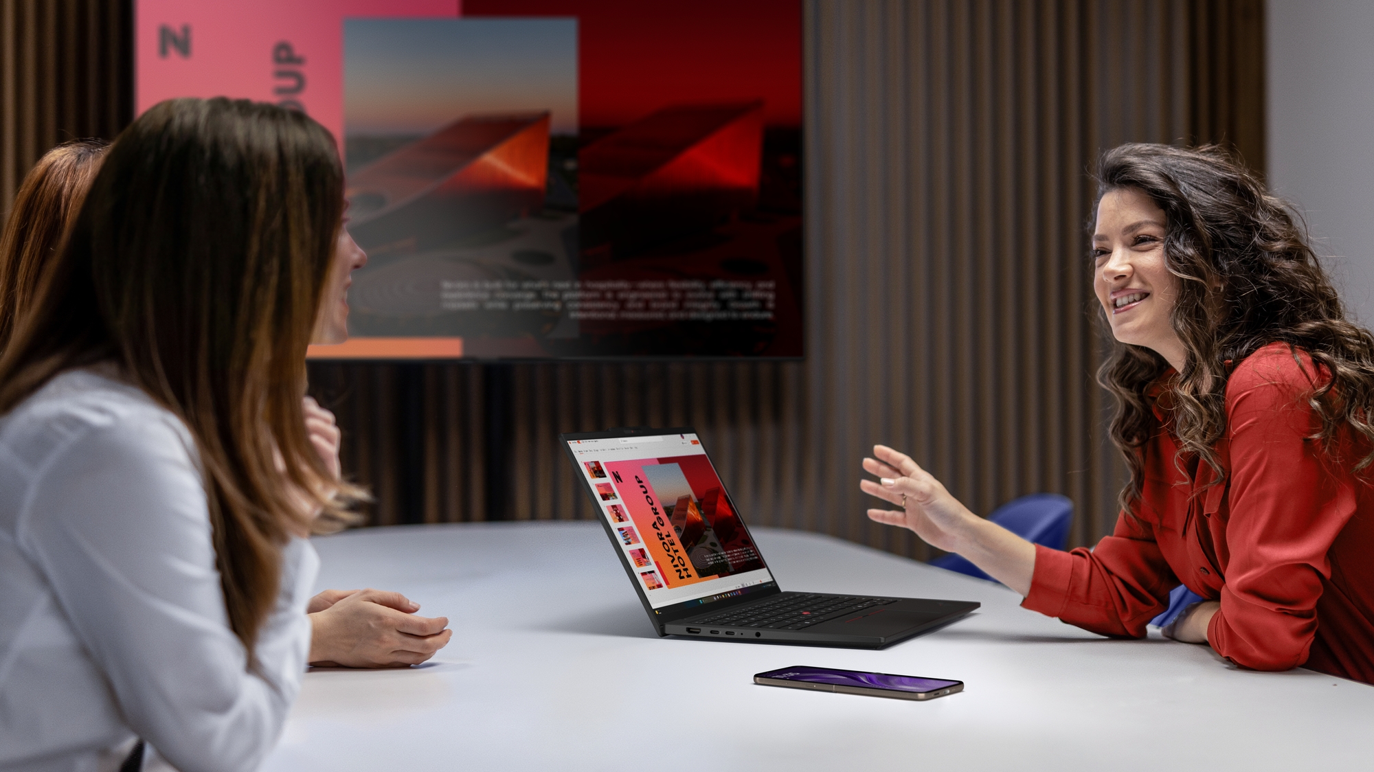 Lenovo ThinkPad T14s laptop open on a table during a work meeting, its side USB-C and HDMI ports visible.