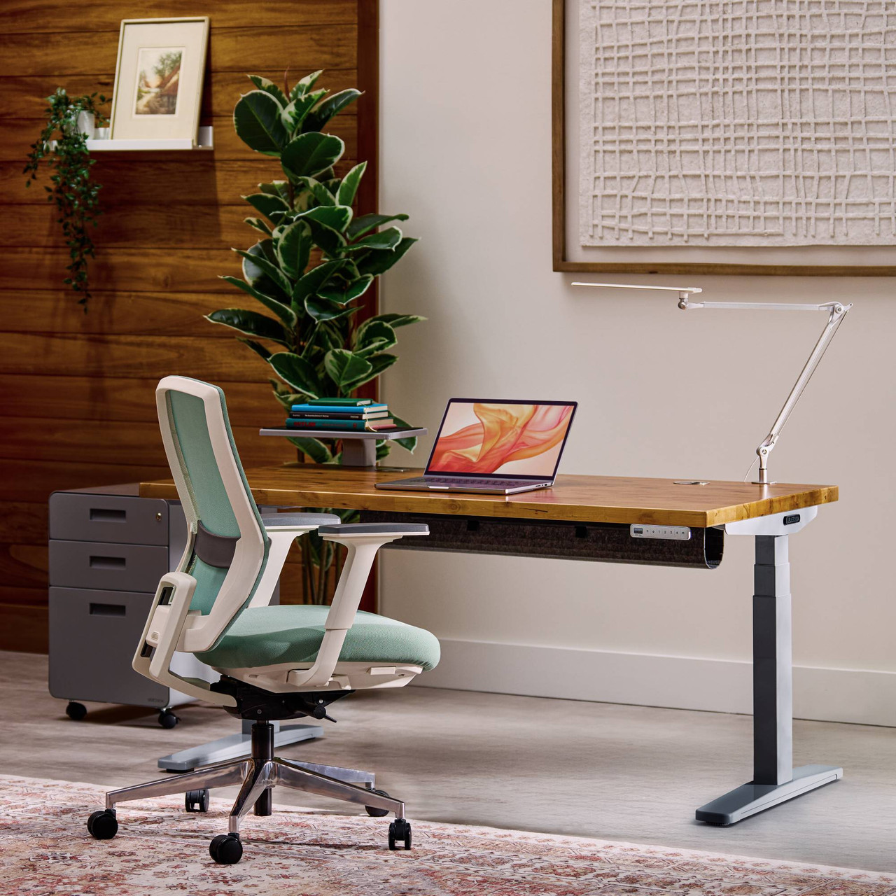 Uplift V3 standing desk with a butcher-block wood top and white frame in a home office